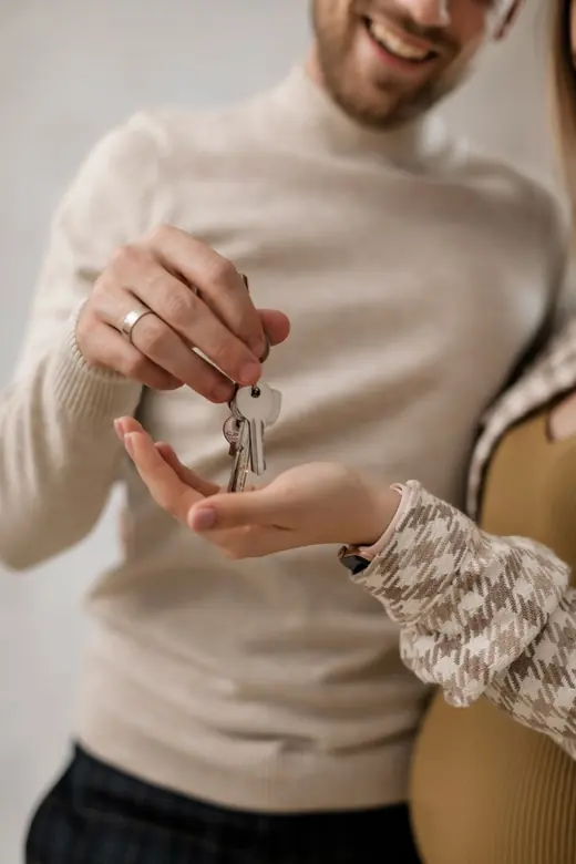 A set of house keys being handed from one person to another indoors