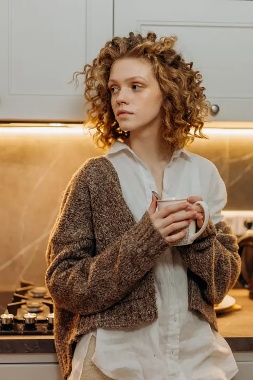 A woman holding a mug in a warmly lit kitchen