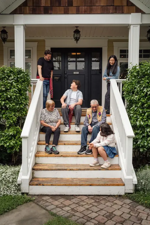 A family sitting together on the front steps of a house