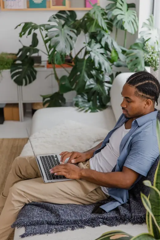 A man working on a laptop in a plant-filled living room